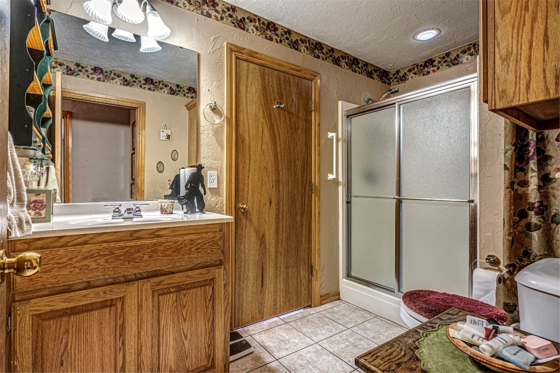 3735 Janet Circle, Mustang, OK 73064 bathroom with toilet, large vanity, a shower with door, tile floors, and a textured ceiling