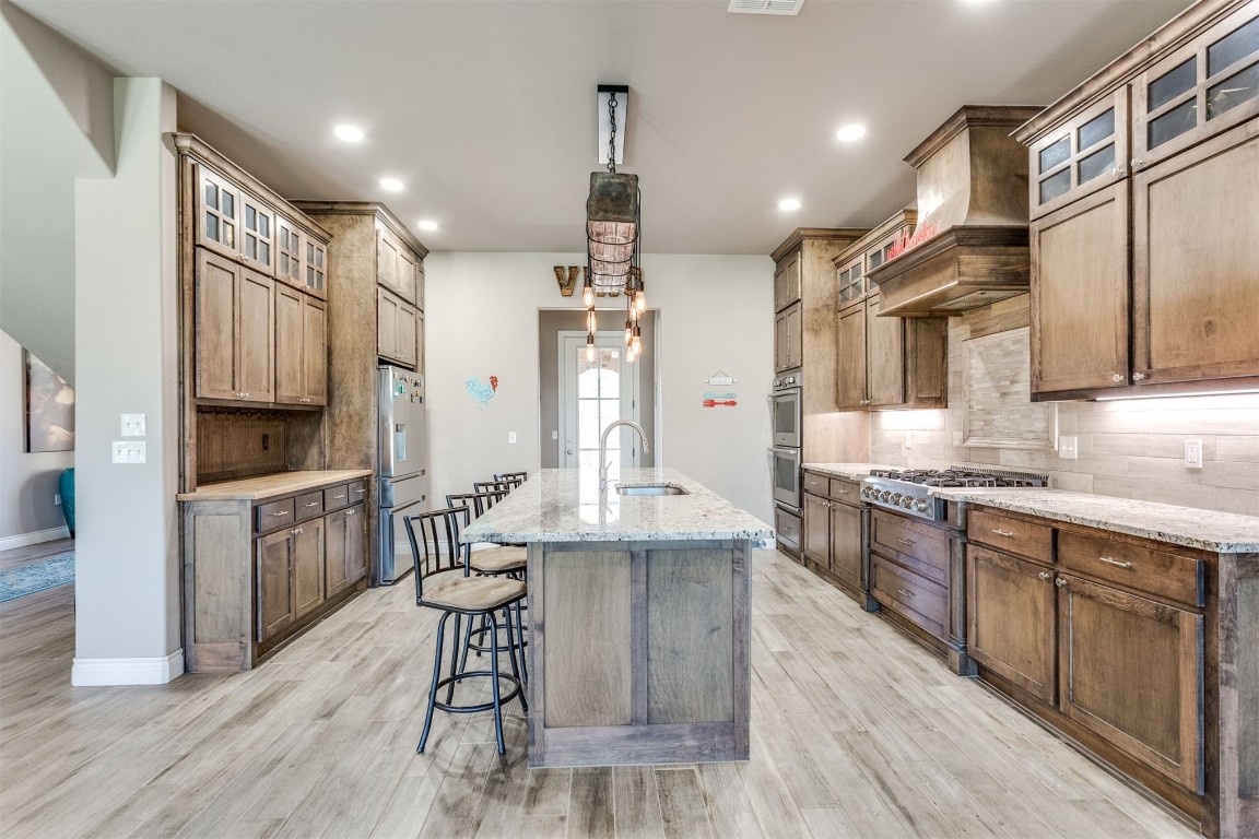 3910 Sienna Ridge, Newcastle, OK 73065 kitchen with light hardwood / wood-style floors, tasteful backsplash, appliances with stainless steel finishes, sink, and an island with sink