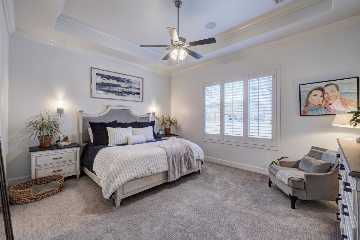 5008 Isle Bridge Court, Edmond, OK 73034 carpeted bedroom with ornamental molding, a raised ceiling, and ceiling fan