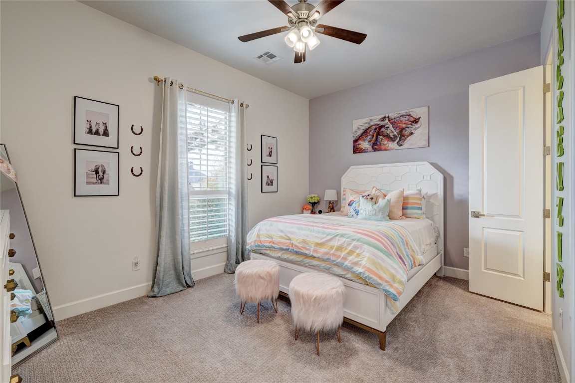 5008 Isle Bridge Court, Edmond, OK 73034 bedroom with light colored carpet and ceiling fan