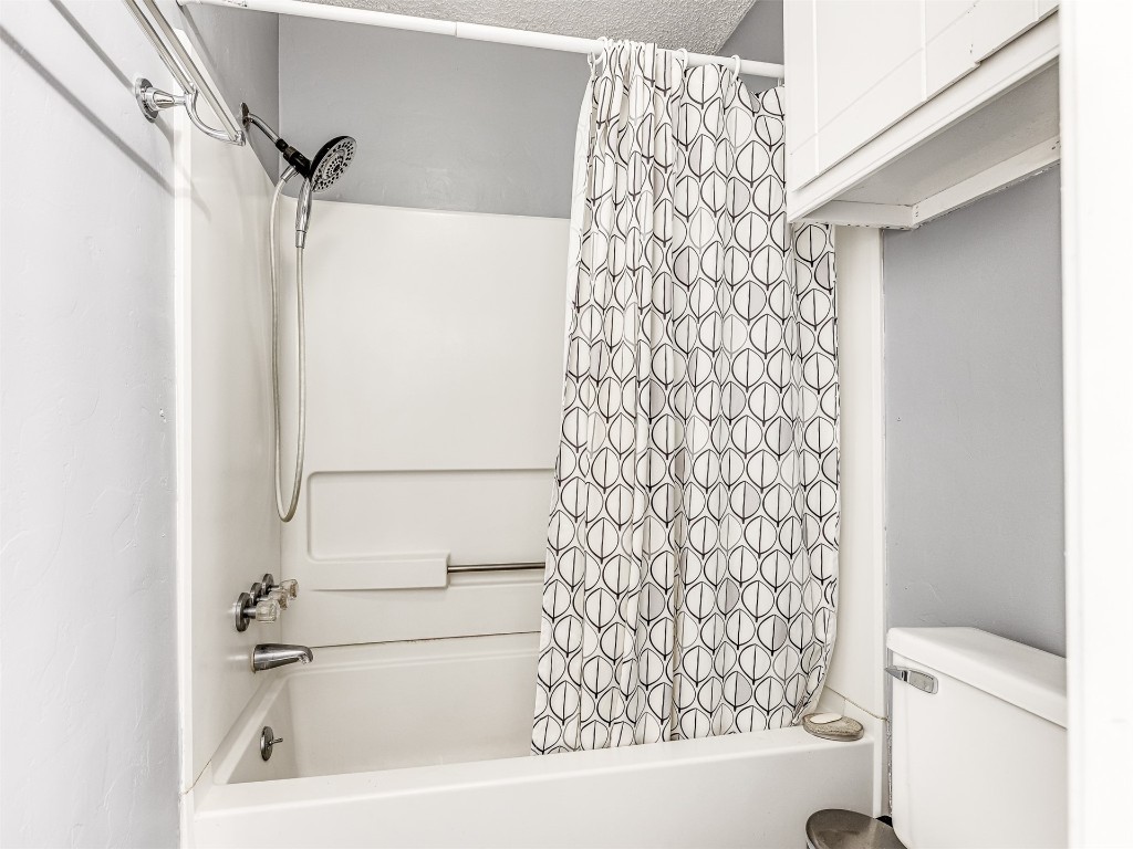 8104 NW 78th Terrace, Oklahoma City, OK 73132 bathroom with toilet and shower / bathtub combination with curtain