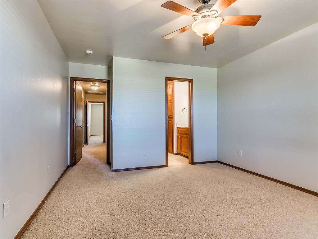 12400 Olivine Terrace, Oklahoma City, OK 73170 unfurnished bedroom with ensuite bath, light carpet, and ceiling fan