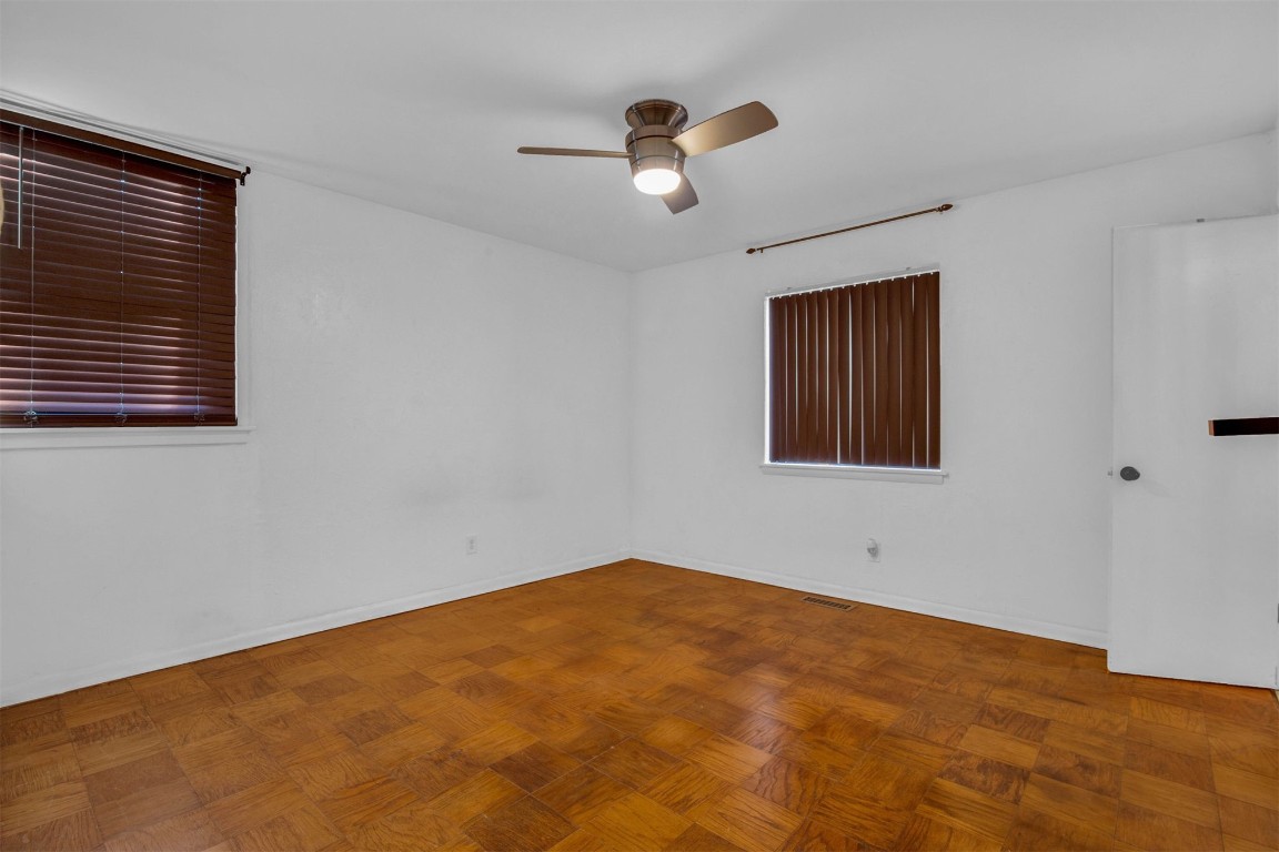 5700 NW 67th Street, Warr Acres, OK 73132 empty room with dark parquet floors and ceiling fan