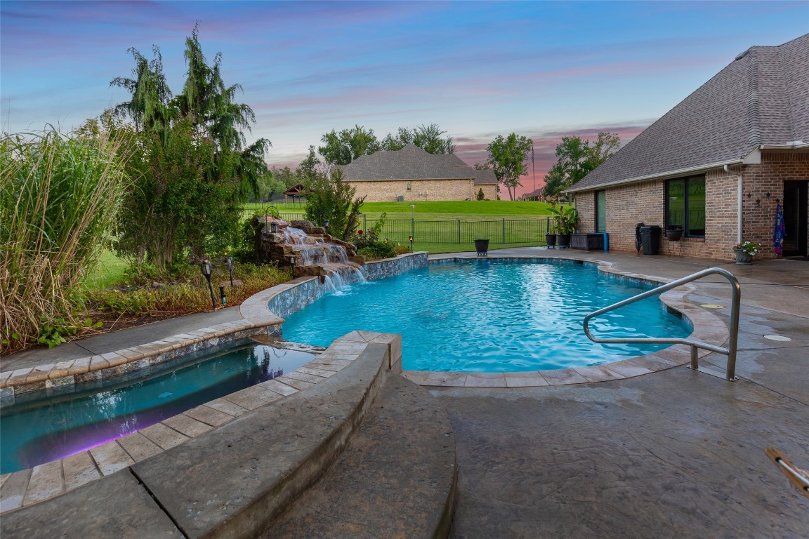 4508 Jacobs Lane, Choctaw, OK 73020 pool at dusk with a yard, pool water feature, and a patio