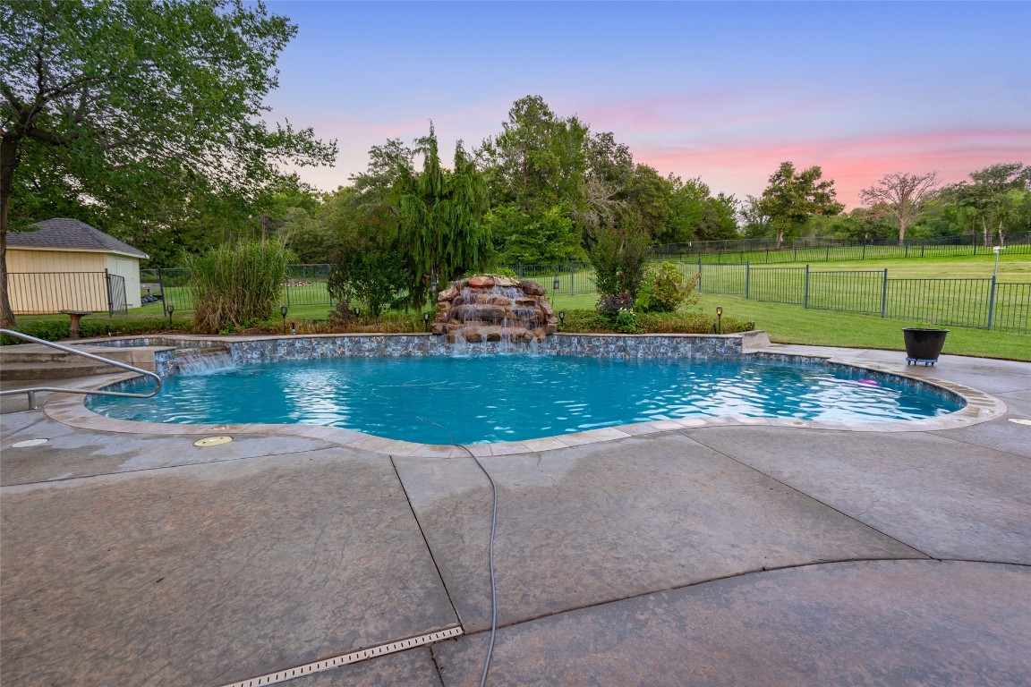 4508 Jacobs Lane, Choctaw, OK 73020 pool at dusk featuring pool water feature, a lawn, and a patio area