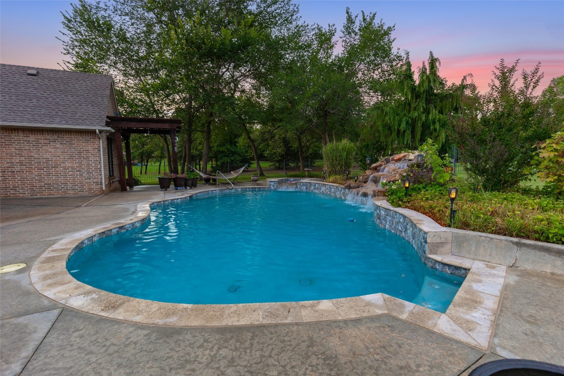 4508 Jacobs Lane, Choctaw, OK 73020 pool at dusk featuring pool water feature and a patio area