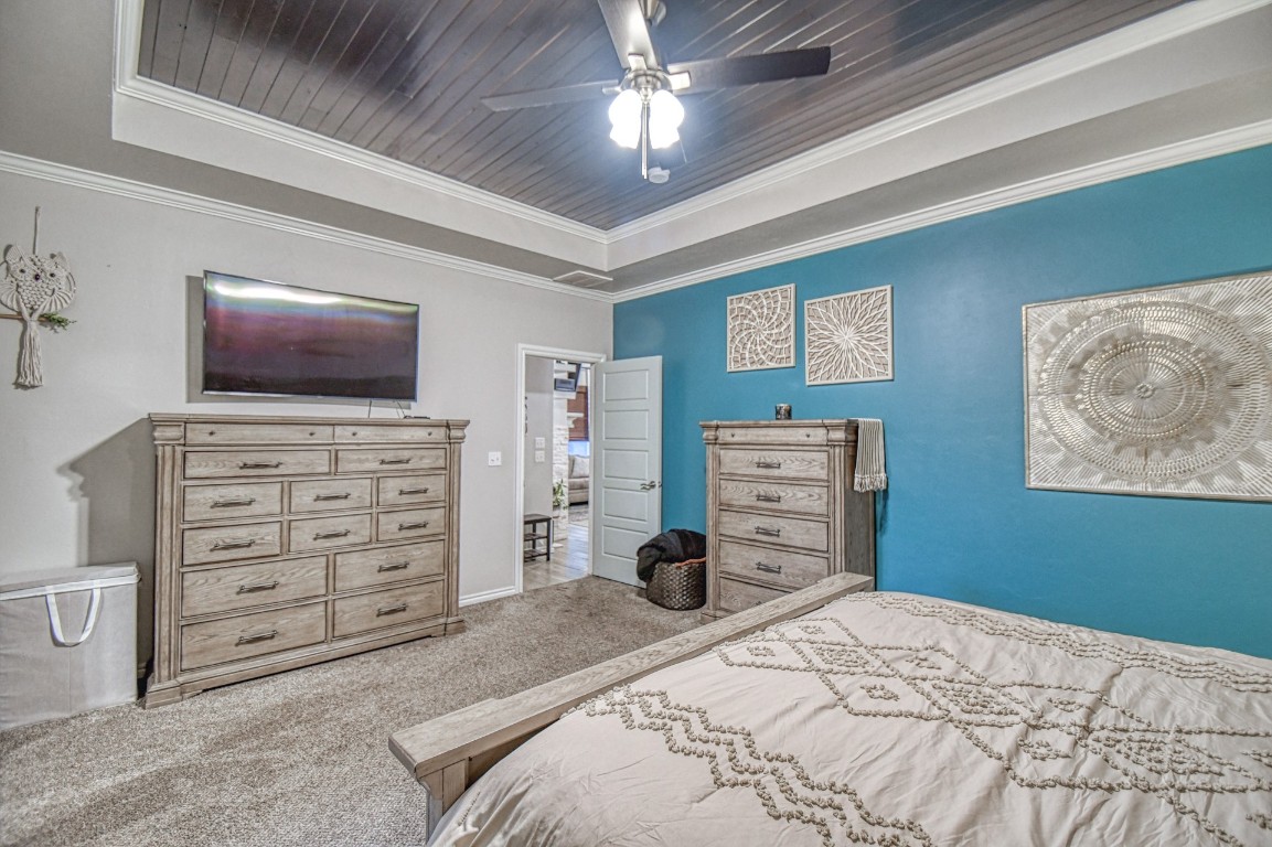 3935 Huntington Parkway, Choctaw, OK 73020 carpeted bedroom with ornamental molding, a raised ceiling, wood ceiling, and ceiling fan