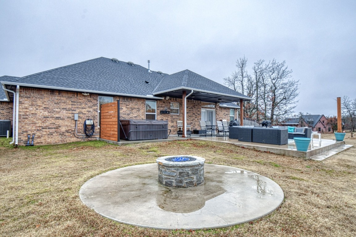 3935 Huntington Parkway, Choctaw, OK 73020 rear view of property featuring a yard, central air condition unit, an outdoor living space with a fire pit, and a patio area