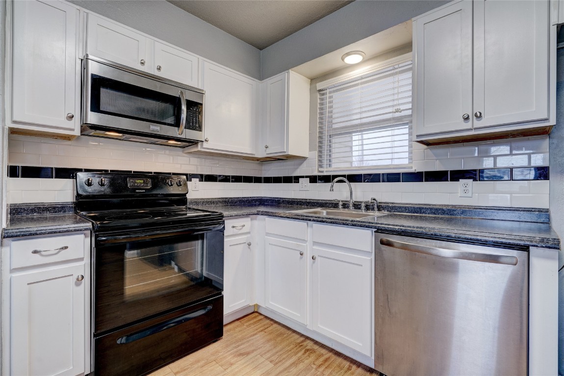 44 SE 57th Street, Oklahoma City, OK 73129 kitchen featuring white cabinetry, light hardwood / wood-style flooring, stainless steel appliances, and backsplash