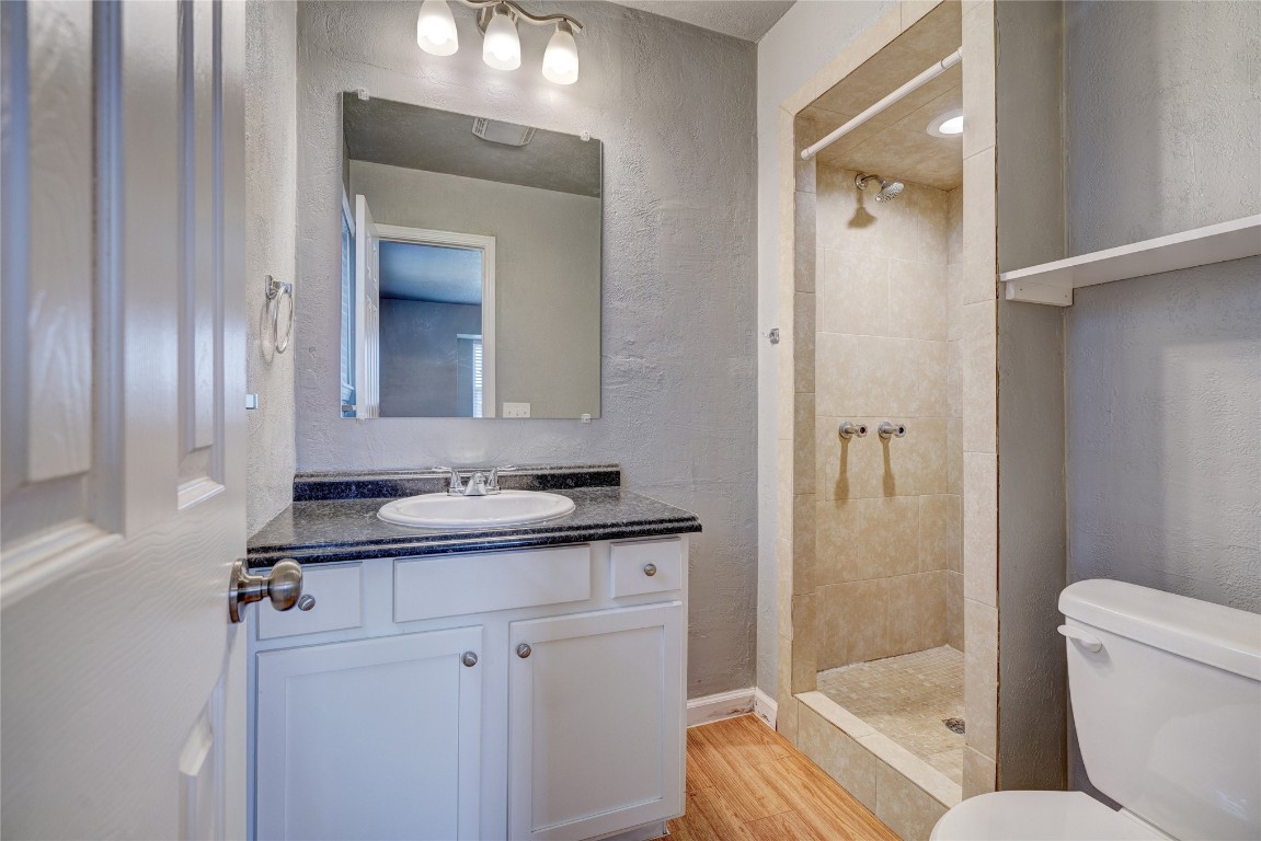 44 SE 57th Street, Oklahoma City, OK 73129 bathroom featuring hardwood / wood-style flooring, vanity, a tile shower, and toilet