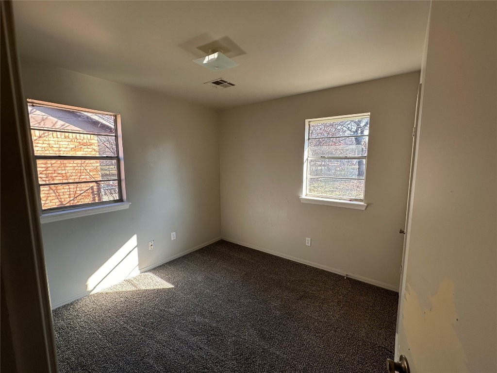 2500 SE 47th Street, Oklahoma City, OK 73129 empty room with dark colored carpet and a wealth of natural light