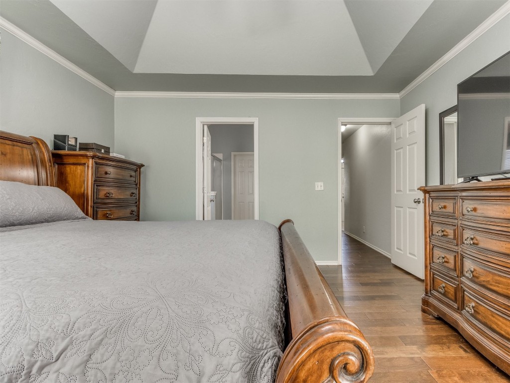 2812 NW 169th Street, Edmond, OK 73012 bedroom with dark wood-type flooring, a tray ceiling, and ornamental molding
