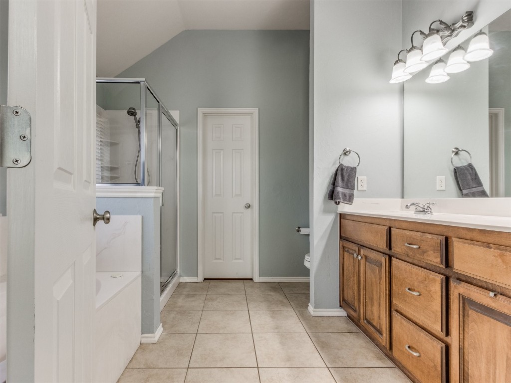2812 NW 169th Street, Edmond, OK 73012 bathroom with walk in shower, vanity, toilet, tile flooring, and vaulted ceiling