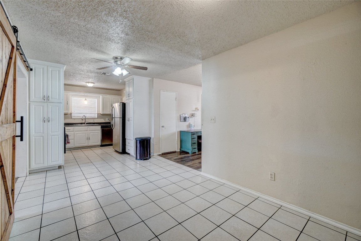 2505 N Hammond Avenue, Oklahoma City, OK 73127 interior space with a textured ceiling, ceiling fan, a barn door, sink, and light tile floors