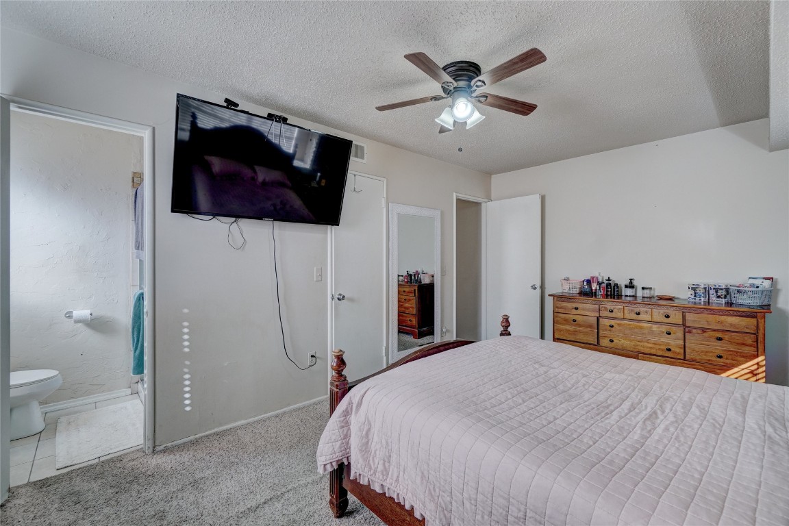 2505 N Hammond Avenue, Oklahoma City, OK 73127 bedroom with light colored carpet, ceiling fan, a textured ceiling, and ensuite bath