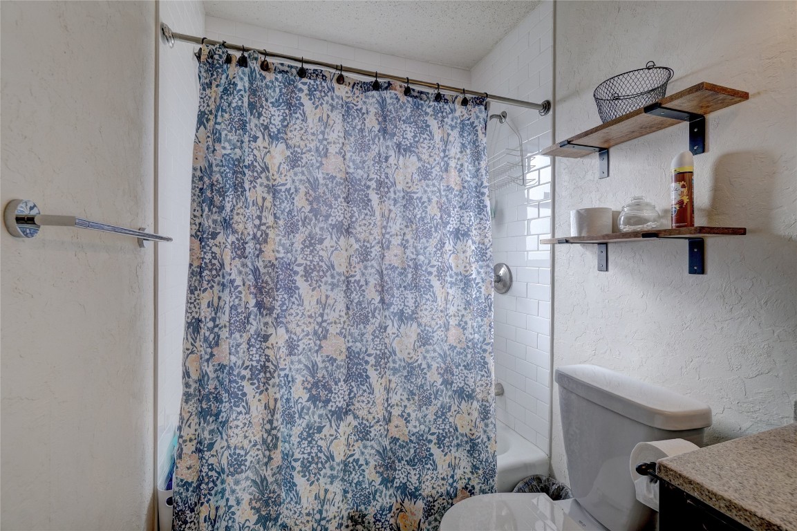 2505 N Hammond Avenue, Oklahoma City, OK 73127 full bathroom with vanity, shower / bath combination with curtain, a textured ceiling, and toilet