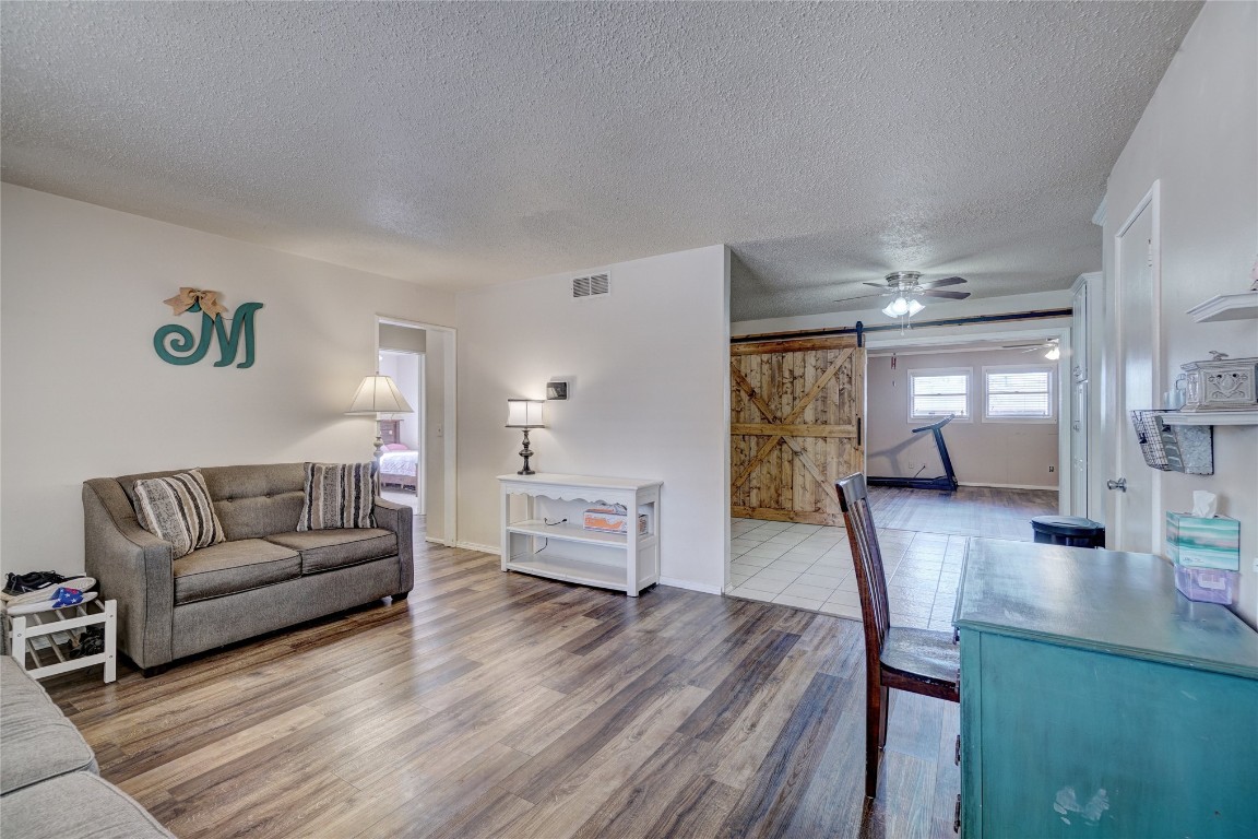 2505 N Hammond Avenue, Oklahoma City, OK 73127 living room featuring hardwood / wood-style flooring, ceiling fan, a textured ceiling, and a barn door