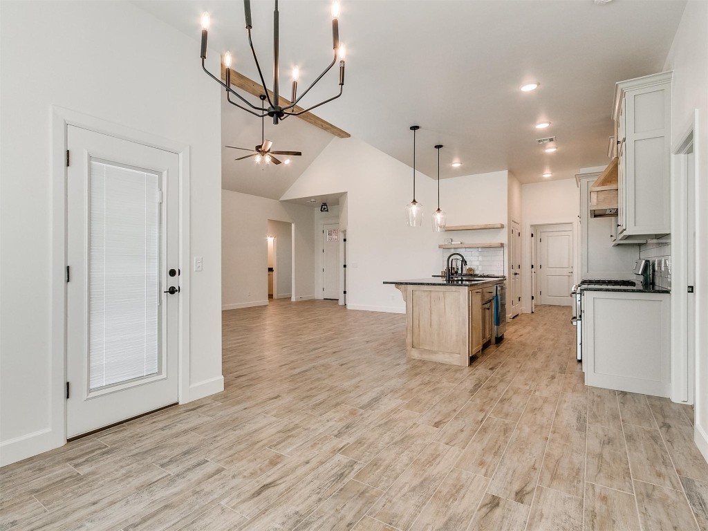 1226 Deer Ridge Boulevard, Tuttle, OK 73089 kitchen featuring ceiling fan with notable chandelier, white cabinetry, light hardwood / wood-style flooring, an island with sink, and stainless steel range with gas stovetop