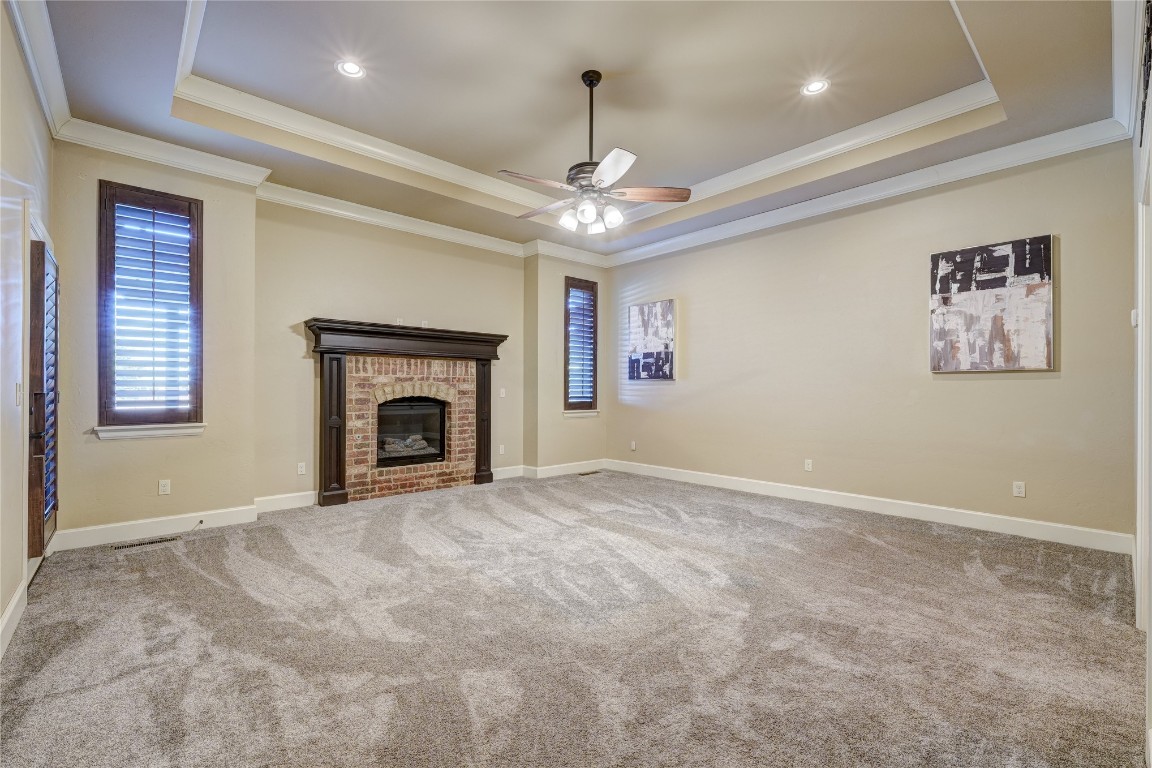 2355 La Belle Rue, Edmond, OK 73034 unfurnished living room with crown molding, ceiling fan, and a raised ceiling