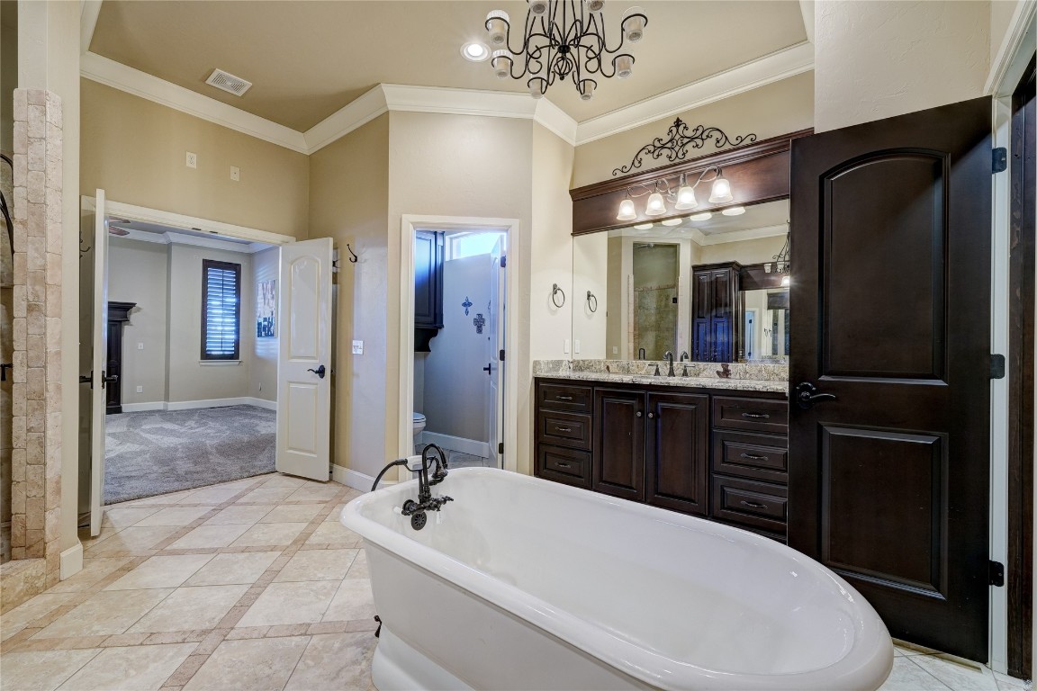 2355 La Belle Rue, Edmond, OK 73034 bathroom with a notable chandelier, tile floors, crown molding, vanity with extensive cabinet space, and a bath to relax in