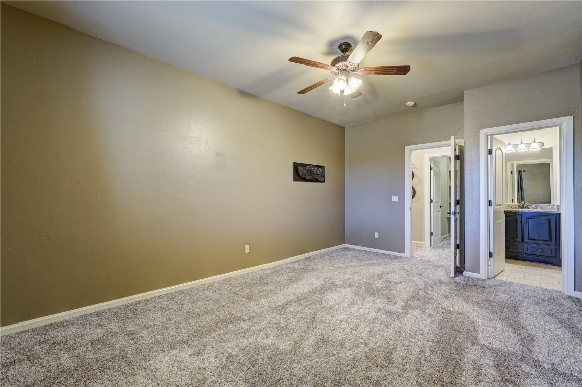 2355 La Belle Rue, Edmond, OK 73034 unfurnished bedroom featuring connected bathroom, ceiling fan, and light colored carpet