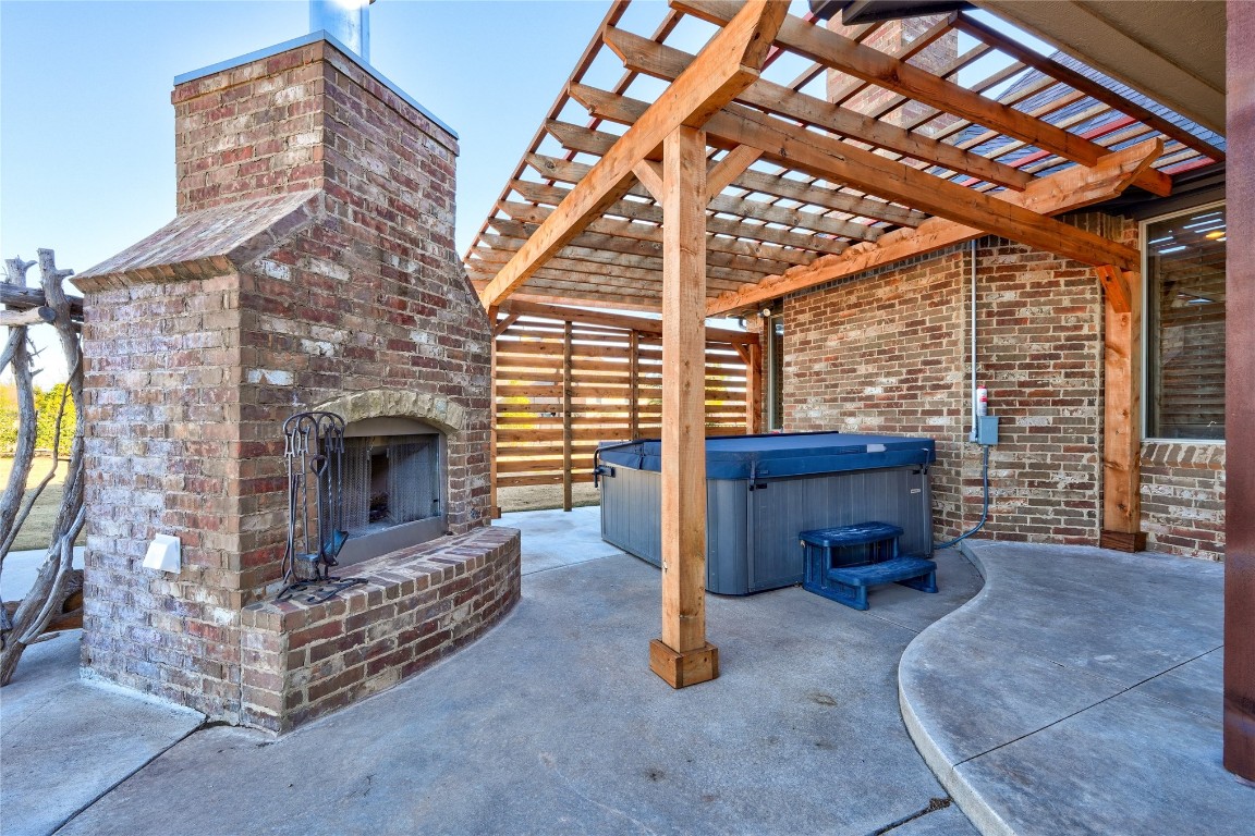 2355 La Belle Rue, Edmond, OK 73034 view of terrace with a pergola, a fireplace, and a hot tub