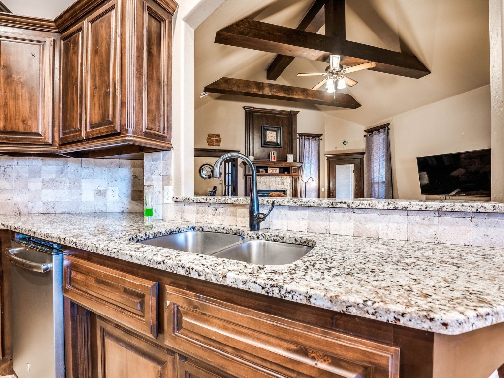 112 Old Home Place, Yukon, OK 73099 kitchen featuring light stone counters, lofted ceiling with beams, backsplash, sink, and ceiling fan
