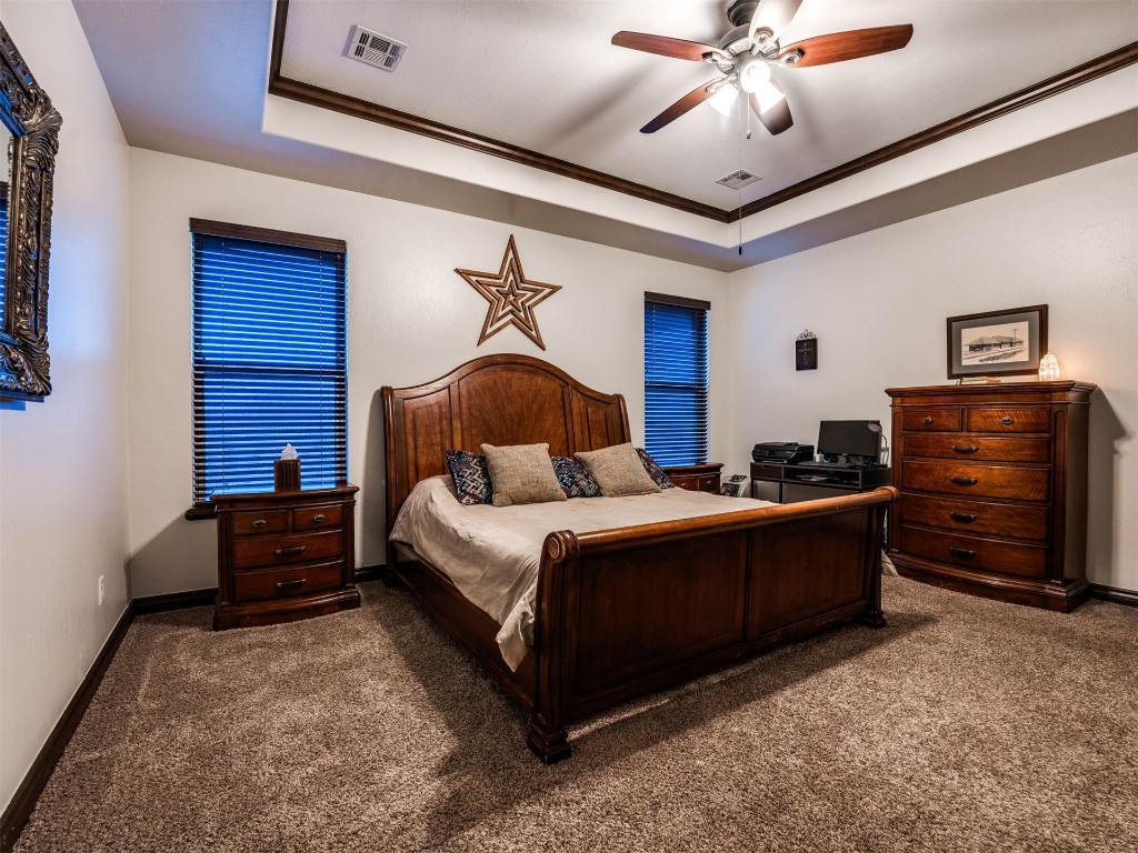 112 Old Home Place, Yukon, OK 73099 bedroom with dark colored carpet, crown molding, ceiling fan, and a tray ceiling