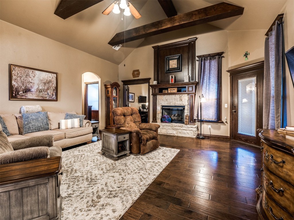 112 Old Home Place, Yukon, OK 73099 living room featuring vaulted ceiling with beams, dark hardwood / wood-style floors, ceiling fan, and a stone fireplace