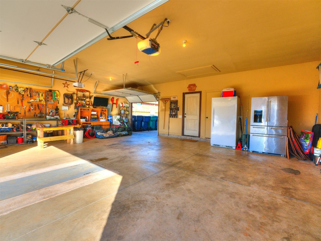 112 Old Home Place, Yukon, OK 73099 garage with a garage door opener, a workshop area, white fridge, and stainless steel refrigerator with ice dispenser