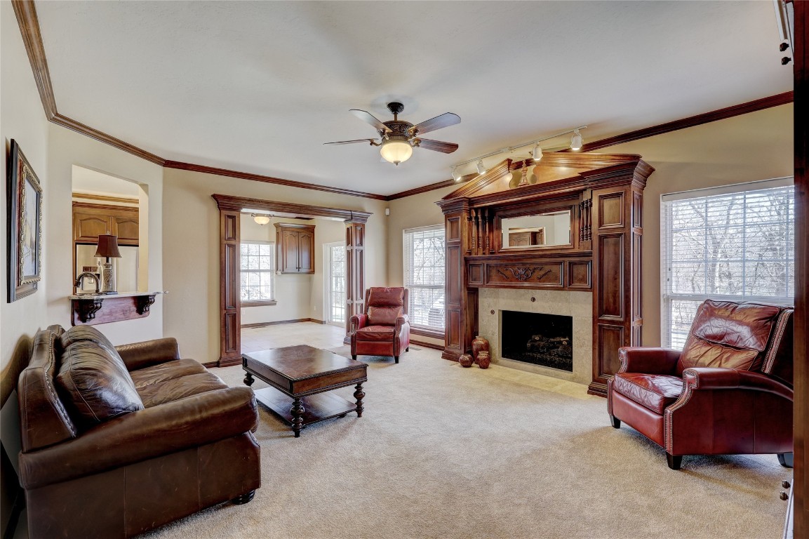 1941 Oak Creek Terrace, Edmond, OK 73034 carpeted living room with ornamental molding, a tile fireplace, and ceiling fan