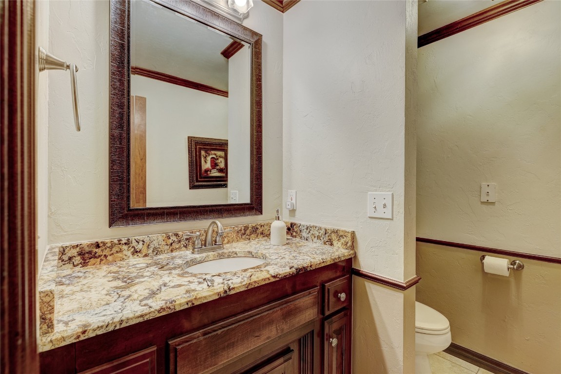 1941 Oak Creek Terrace, Edmond, OK 73034 bathroom with large vanity, tile flooring, ornamental molding, and toilet