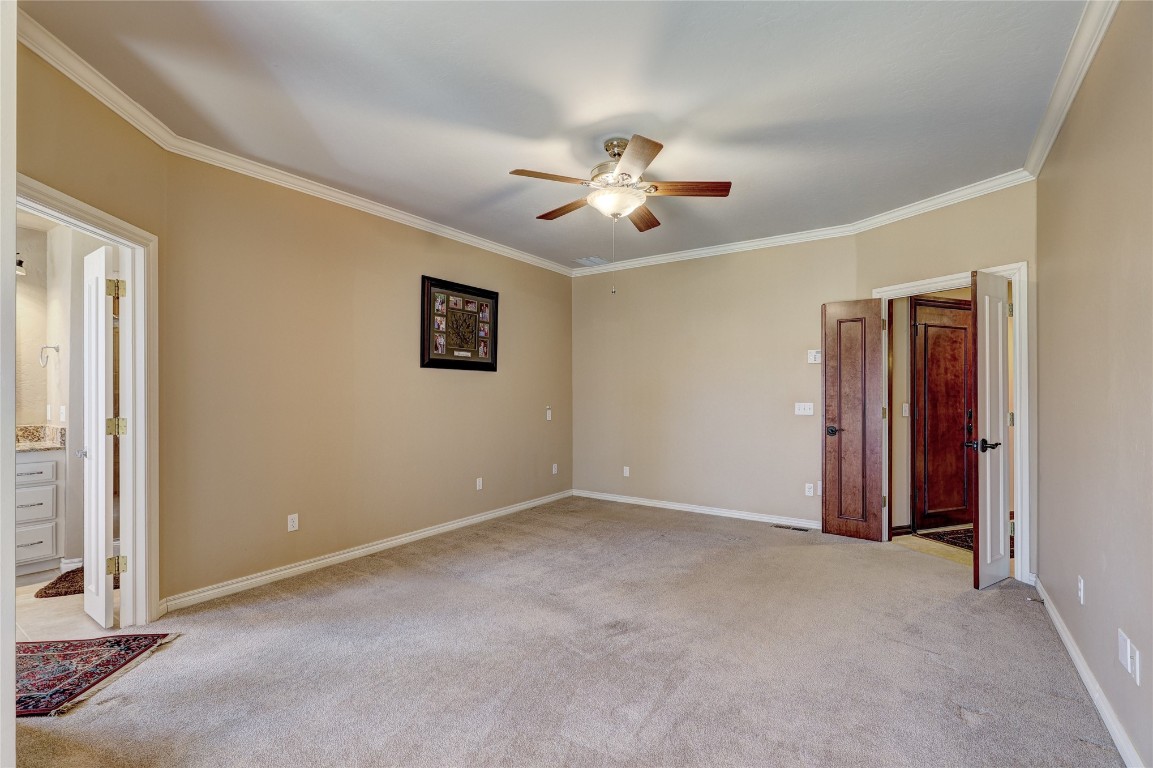 1941 Oak Creek Terrace, Edmond, OK 73034 carpeted spare room featuring crown molding and ceiling fan