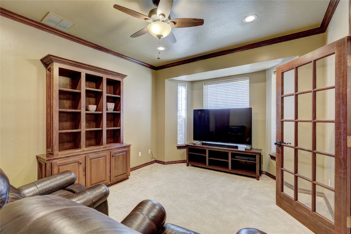 1941 Oak Creek Terrace, Edmond, OK 73034 carpeted living room with crown molding and ceiling fan