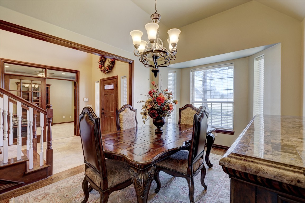 1941 Oak Creek Terrace, Edmond, OK 73034 dining area featuring ceiling fan with notable chandelier, light tile floors, and vaulted ceiling