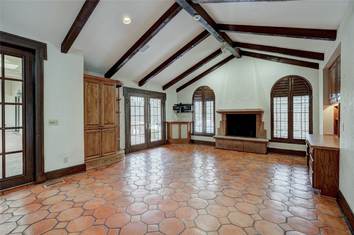 3900 S Bryant Avenue, Edmond, OK 73013 unfurnished living room with high vaulted ceiling, french doors, beamed ceiling, a fireplace, and light tile floors