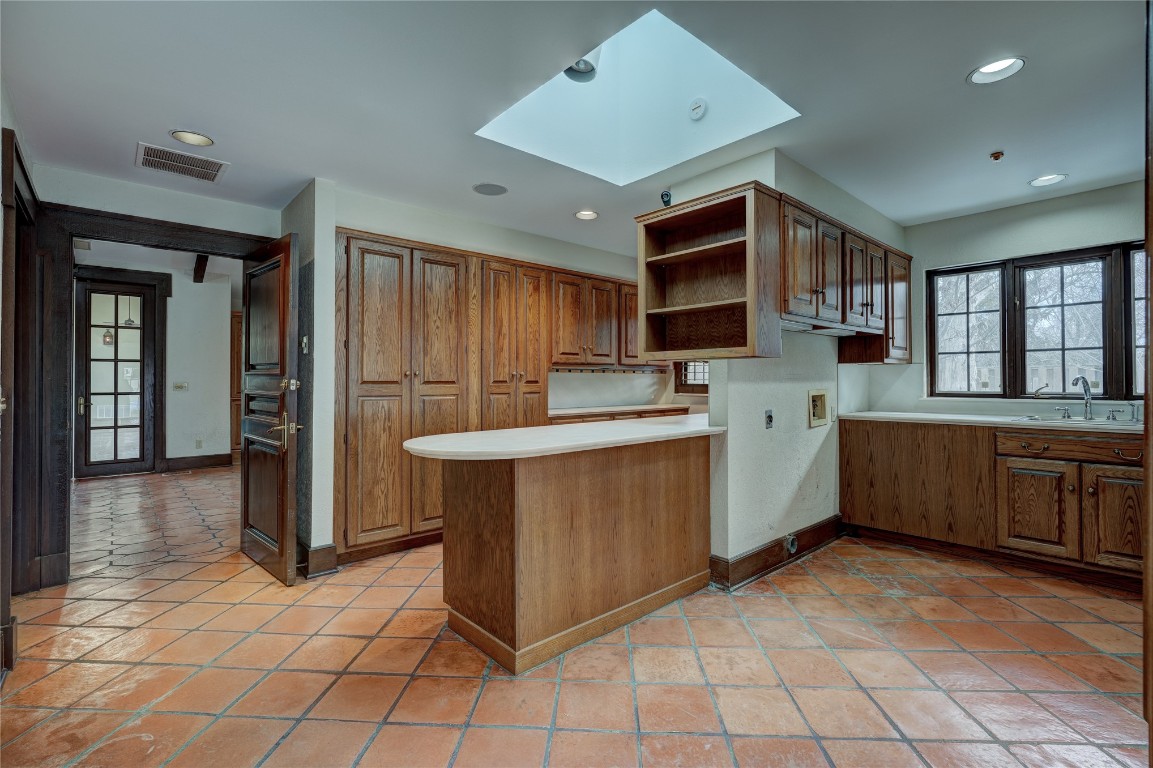 3900 S Bryant Avenue, Edmond, OK 73013 kitchen with sink, a skylight, light tile floors, and kitchen peninsula