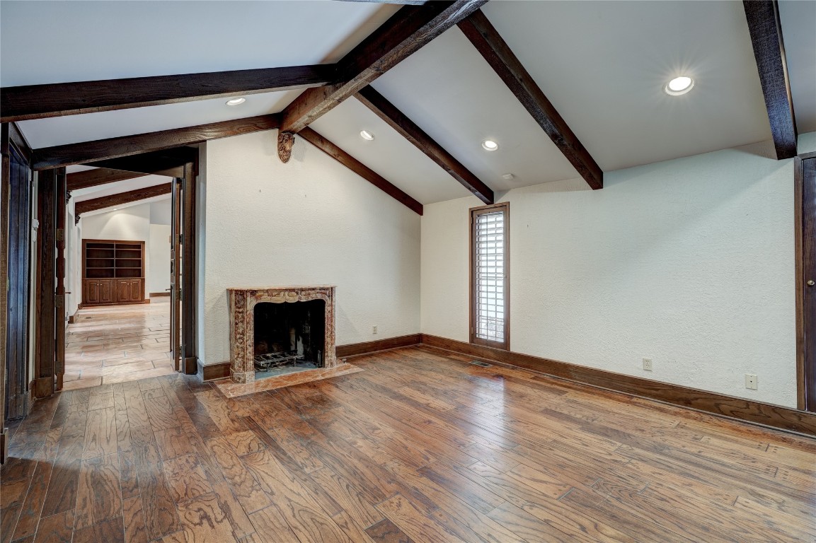 3900 S Bryant Avenue, Edmond, OK 73013 unfurnished living room with dark hardwood / wood-style flooring, a premium fireplace, and vaulted ceiling with beams