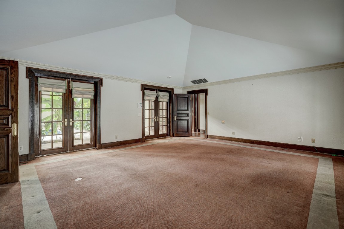 3900 S Bryant Avenue, Edmond, OK 73013 carpeted empty room featuring high vaulted ceiling, crown molding, and french doors
