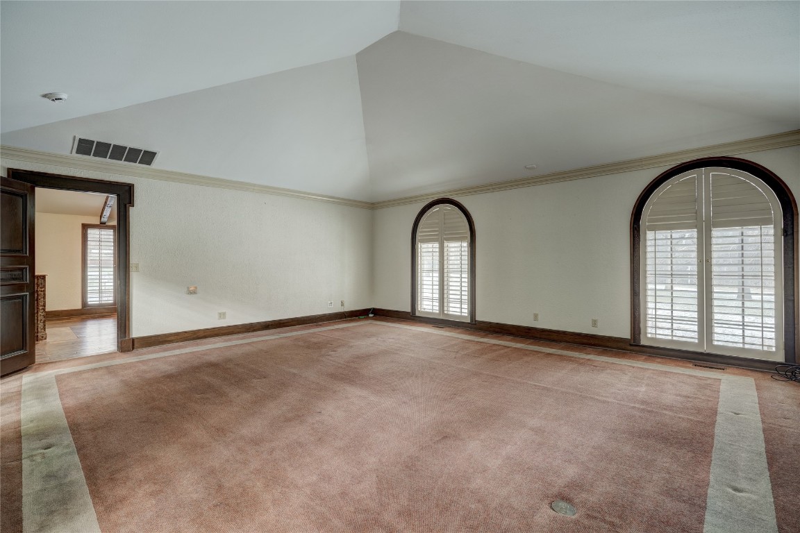 3900 S Bryant Avenue, Edmond, OK 73013 spare room with light carpet, ornamental molding, and high vaulted ceiling