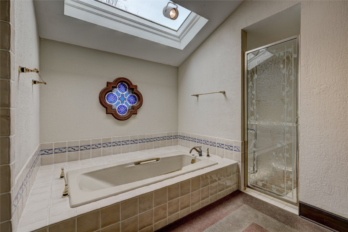 3900 S Bryant Avenue, Edmond, OK 73013 bathroom with shower with separate bathtub and lofted ceiling with skylight