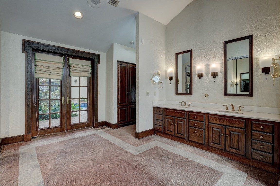 3900 S Bryant Avenue, Edmond, OK 73013 bathroom featuring dual bowl vanity, vaulted ceiling, and french doors