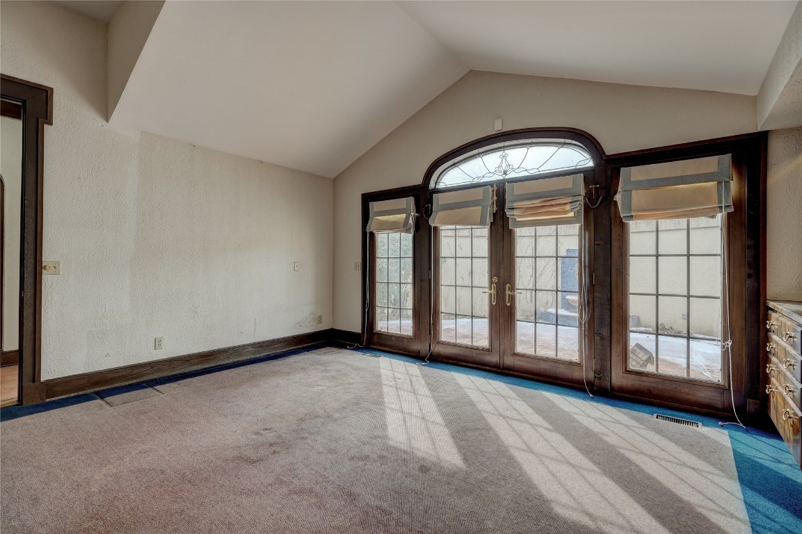 3900 S Bryant Avenue, Edmond, OK 73013 empty room featuring vaulted ceiling, light colored carpet, and french doors