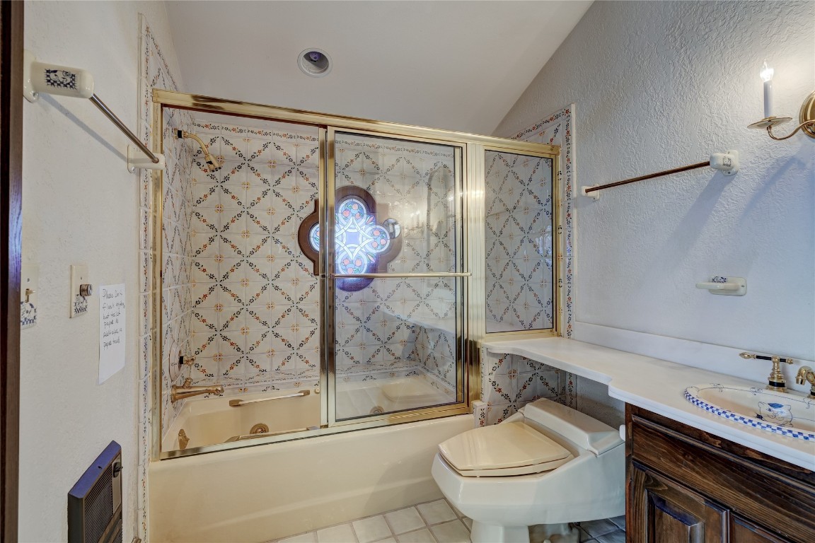 3900 S Bryant Avenue, Edmond, OK 73013 full bathroom featuring vanity, vaulted ceiling, shower / bath combination with glass door, toilet, and tile floors