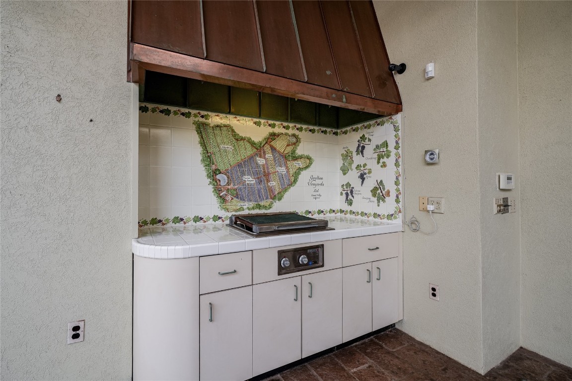 3900 S Bryant Avenue, Edmond, OK 73013 kitchen featuring white cabinets, tile counters, and tasteful backsplash