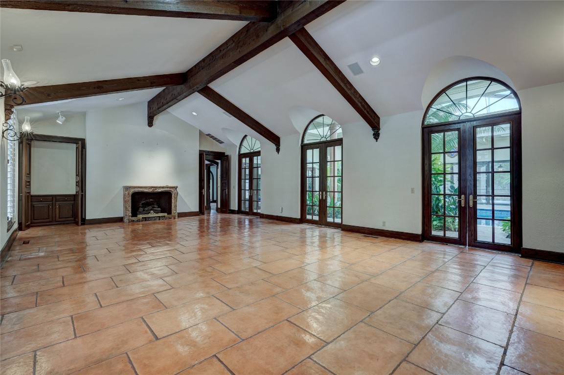 3900 S Bryant Avenue, Edmond, OK 73013 unfurnished living room with beamed ceiling, light tile floors, a notable chandelier, french doors, and high vaulted ceiling