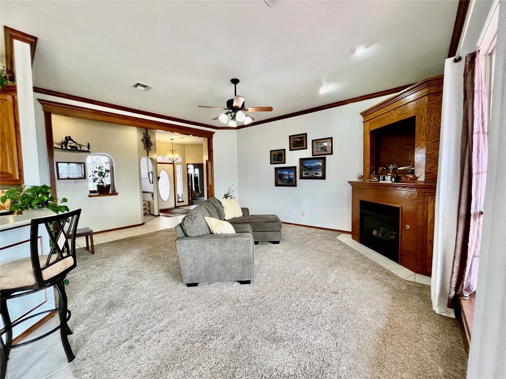 5808 E McMillin Dr, Tuttle, OK 73089 carpeted living room featuring ceiling fan with notable chandelier and ornamental molding