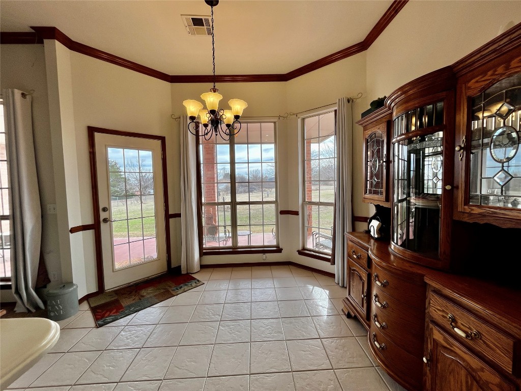 5808 E McMillin Dr, Tuttle, OK 73089 doorway to outside with plenty of natural light, an inviting chandelier, crown molding, and light tile floors