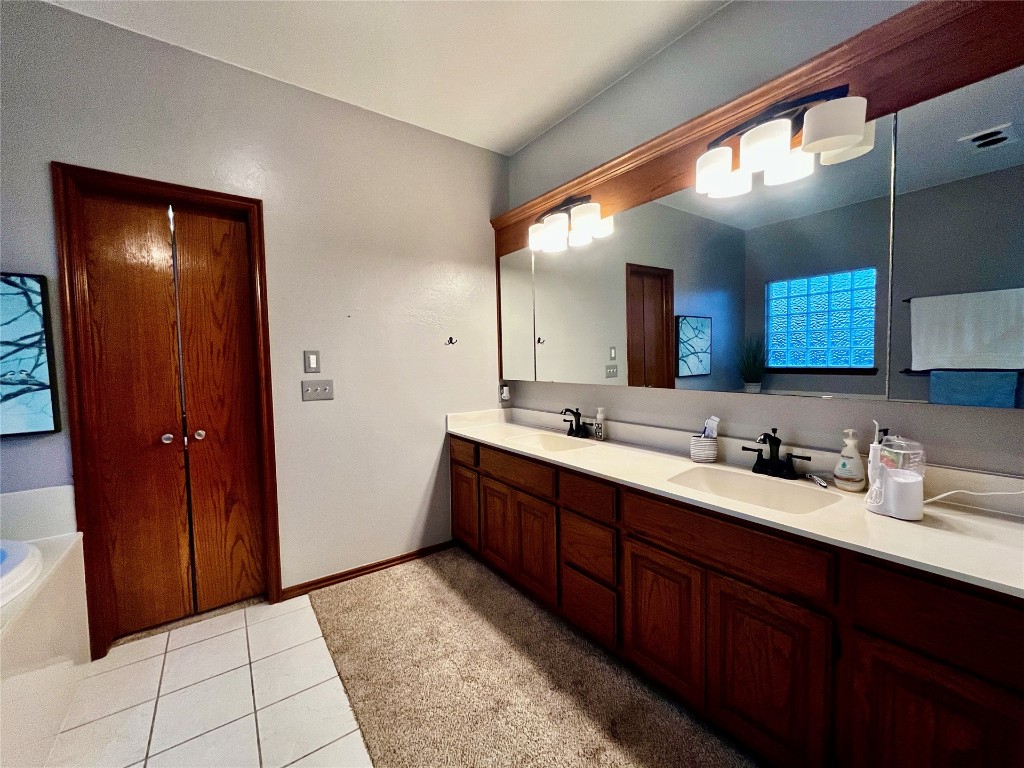 5808 E McMillin Dr, Tuttle, OK 73089 bathroom with double vanity, a bath to relax in, and tile flooring