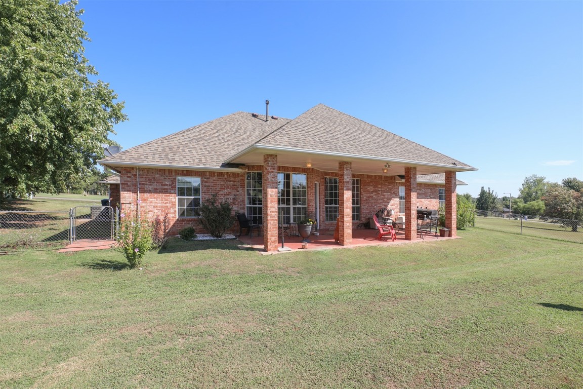 5808 E McMillin Dr, Tuttle, OK 73089 back of property featuring a lawn and a patio area